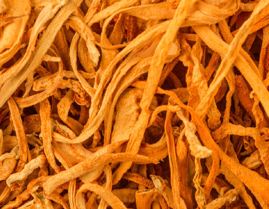 Close-up of dried mushroom strips with a golden-orange hue, showcasing their fibrous texture and natural curled shapes.